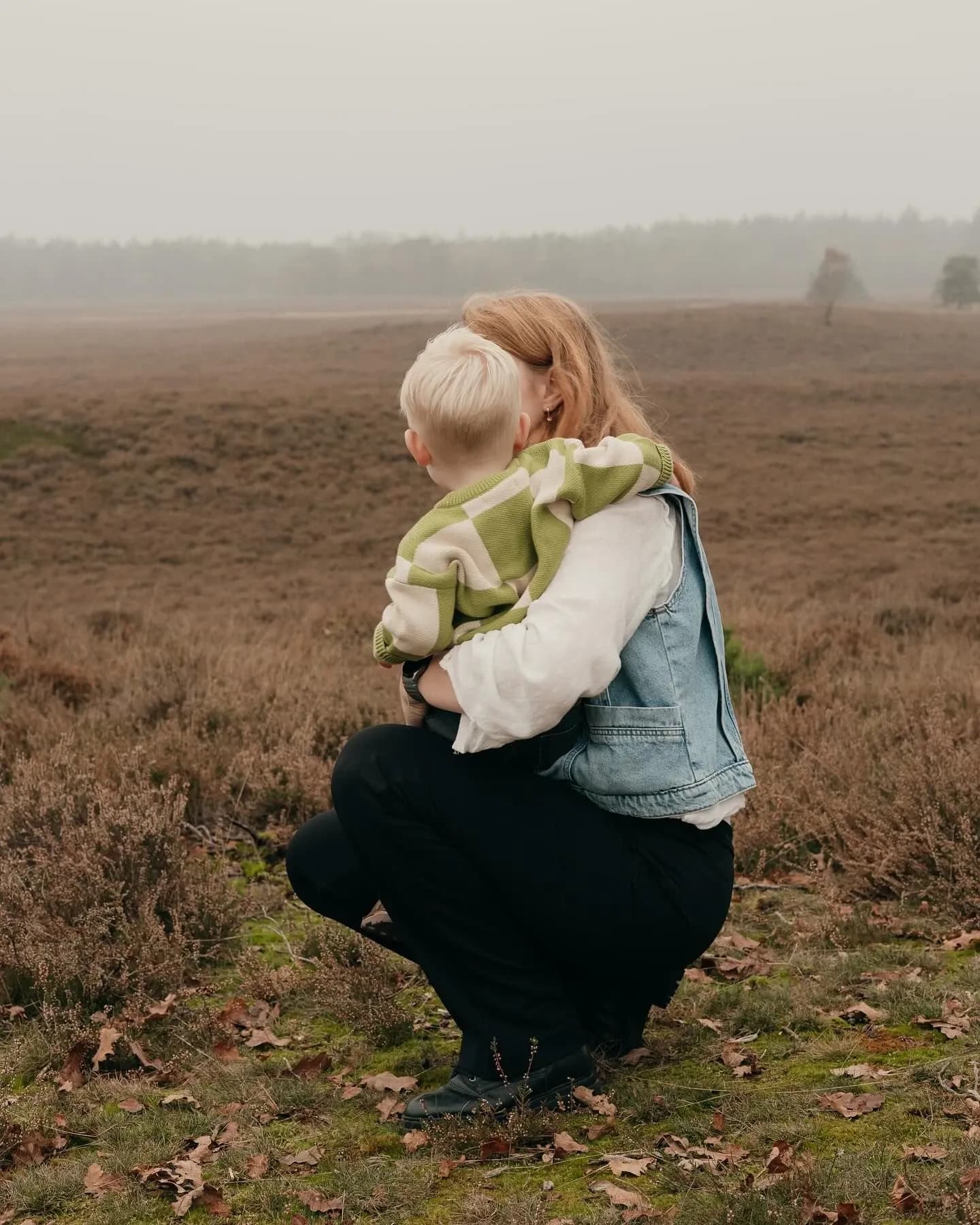 Moeder tilt haar kind op in de heide
